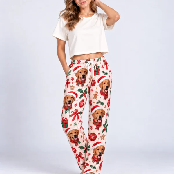Woman posing in Christmas pajama pants with golden retriever faces in Santa hats — MyDogPics
