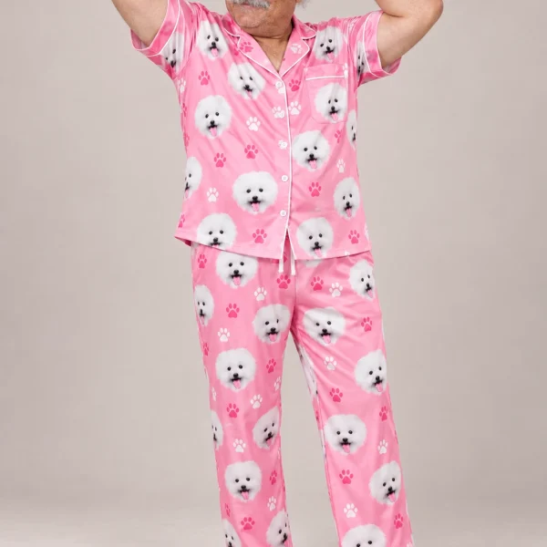 Man posing in couples Christmas pajamas, white Pomeranian faces on pink paw-print satin — MyDogPics