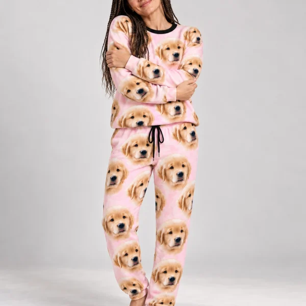 Woman wearing cozy pajamas covered in golden retriever puppy faces on blush pink fabric — MyDogPics