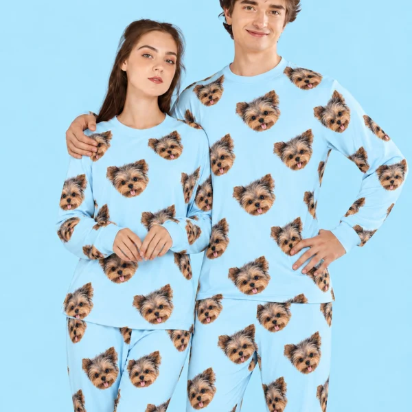 Couple posing in family matching pajamas, Yorkshire terrier faces on light blue fabric — MyDogPics
