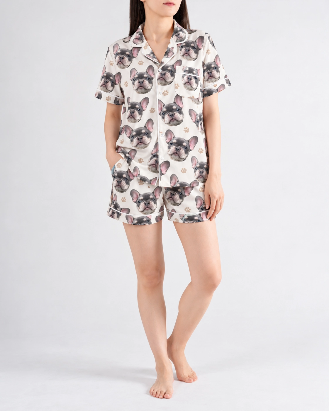 Frenchie Pajamas – Front View | MyDogPics Woman wearing frenchie pajamas covered in grey French bulldog faces on ivory satin with black paw prints — MyDogPics
