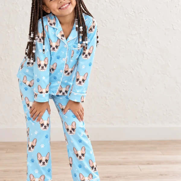 Girl wearing girls Christmas pajamas covered in cream French bulldog faces on light blue paw-print satin — MyDogPics