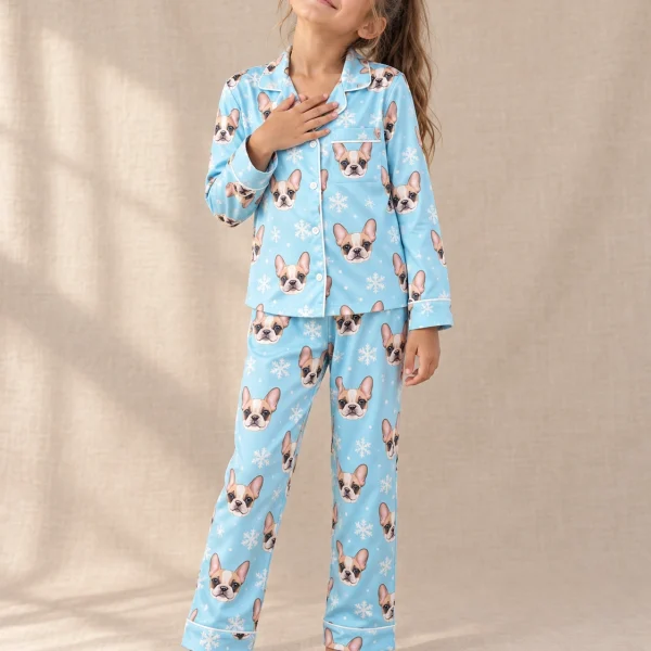 Girl wearing kids plaid pajamas covered in cream French bulldog faces on blue snowflake satin — MyDogPics