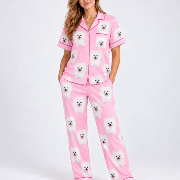 Woman posing in matching couple pajamas, white Pomeranian faces on pink satin with hearts and paw prints — MyDogPics