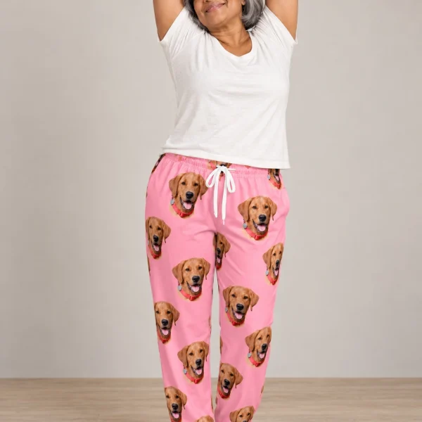 Woman posing in matching pajama pants, golden retriever faces on pink fabric — MyDogPics