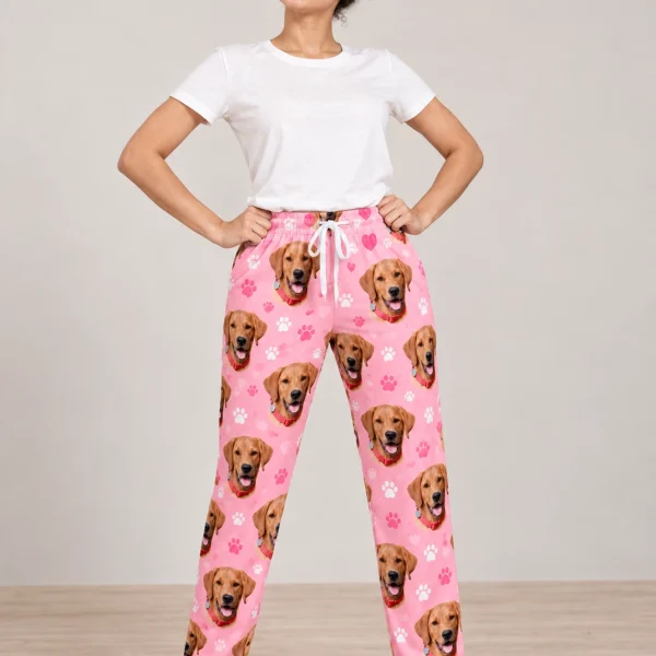 Woman wearing pink pajama pants covered in golden retriever faces on pink paw-print fabric — MyDogPics