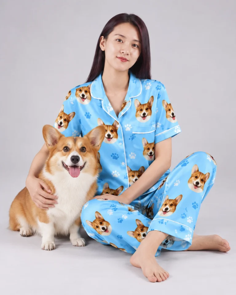 Woman in blue pajamas printed with corgi faces sitting beside her corgi, a new years eve pajamas idea with the dog