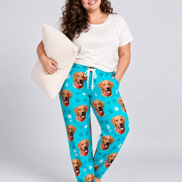Woman wearing plaid pajama pants covered in golden retriever faces on teal paw-print fabric — MyDogPics