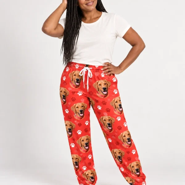 Woman wearing red pajama pants covered in golden retriever faces on red paw-print fabric — MyDogPics