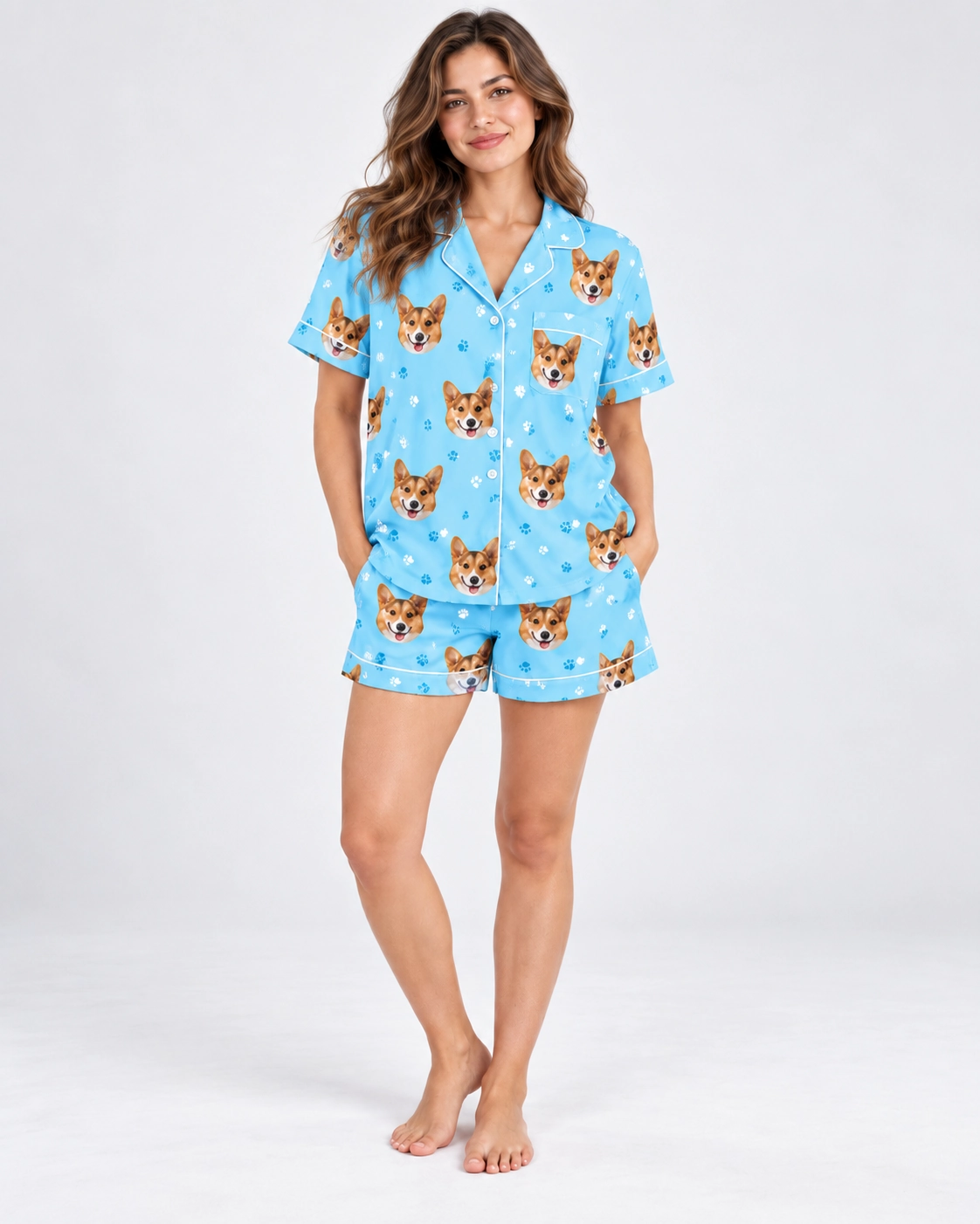 Short Sleeve Satin Pajama Set – Front View | MyDogPics Woman wearing a short sleeve satin pajama set covered in corgi faces on sky blue satin with white piping — MyDogPics