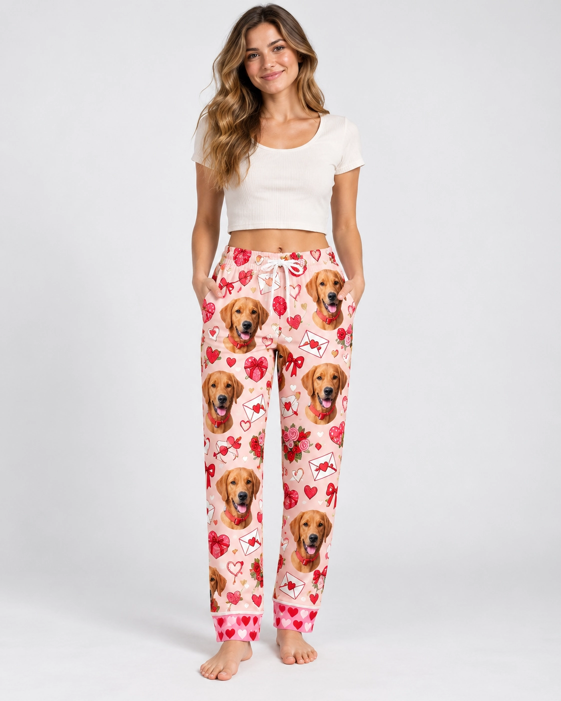 Valentine Pajama Pants – Front View | MyDogPics Woman wearing Valentine pajama pants covered in golden retriever faces on a pink Valentine hearts print — MyDogPics