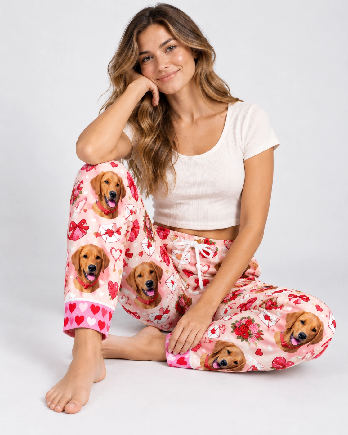 Valentine Pajama Pants – Sitting | MyDogPics Woman sitting in Valentine pajama pants covered in golden retriever faces — MyDogPics