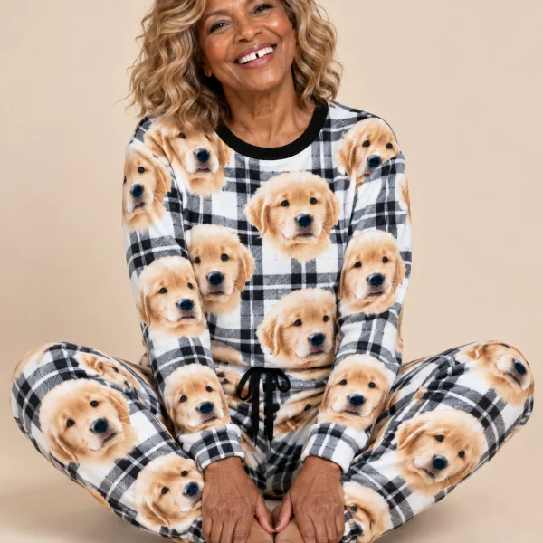 Woman sitting in womens Christmas pajamas covered in golden retriever puppy faces — MyDogPics