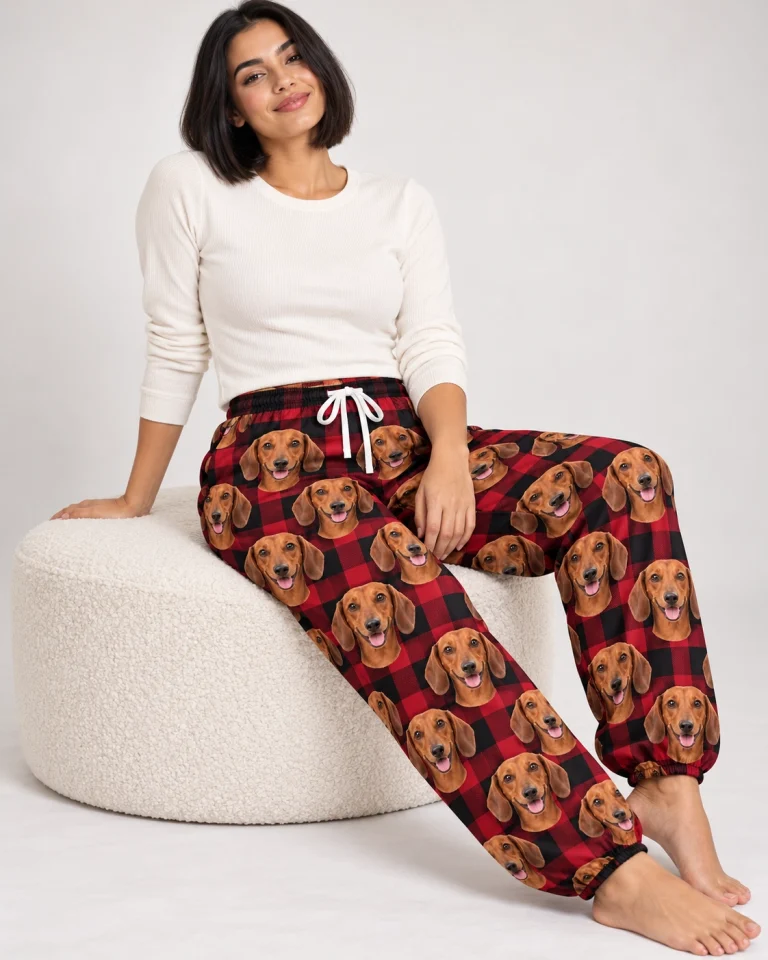Woman sitting in dachshund Christmas pants covered in red smooth-coated Dachshund faces — MyDogPics