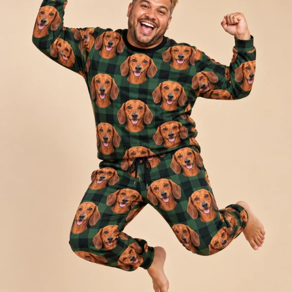 Man posing in a dachshund pajama set, red smooth-coated Dachshund faces on green plaid fabric — MyDogPics