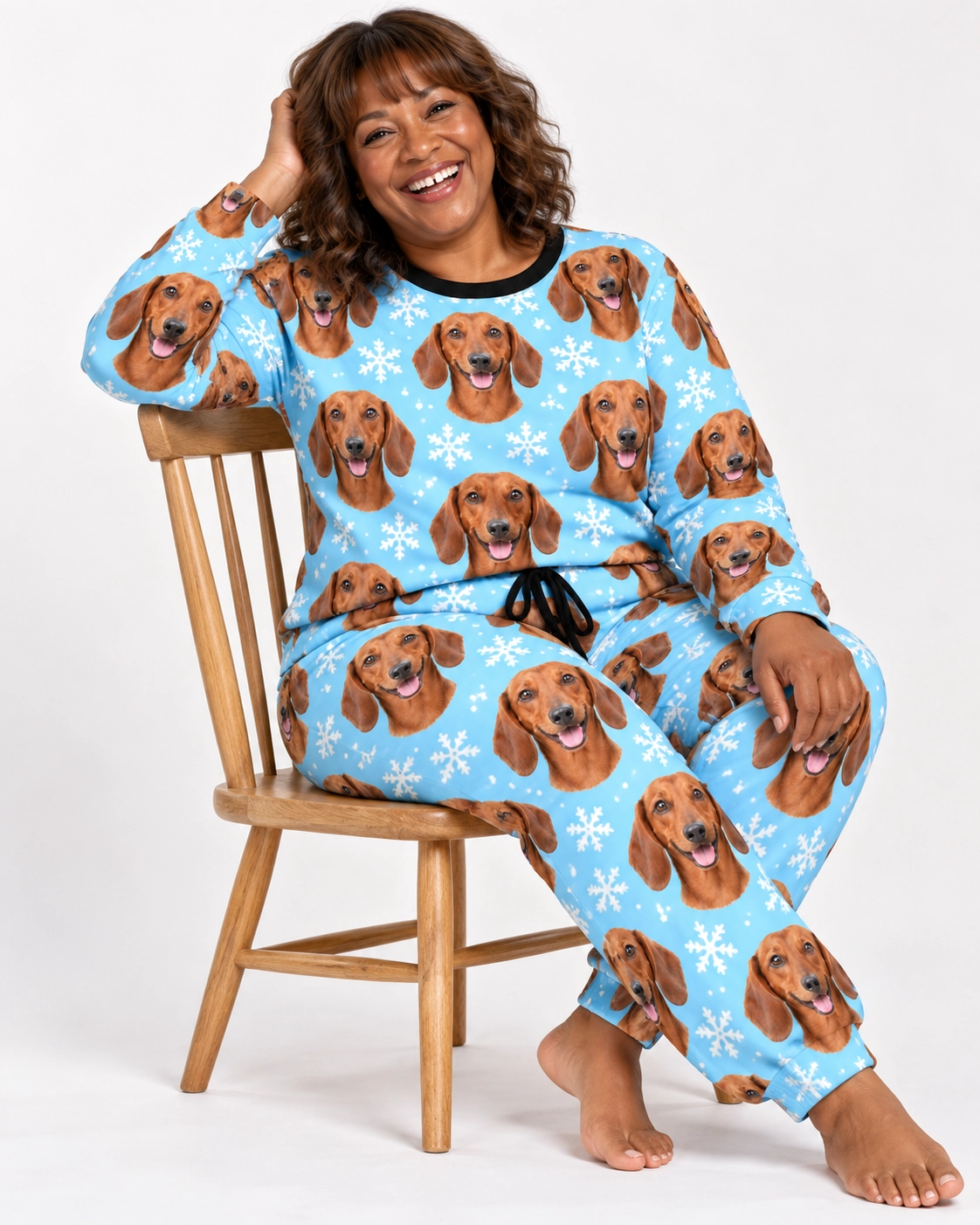 Dachshund Winter Pajamas – Sitting, Light Blue Snowflake | MyDogPics Woman sitting in dachshund winter pajamas covered in red smooth-coated Dachshund faces — MyDogPics