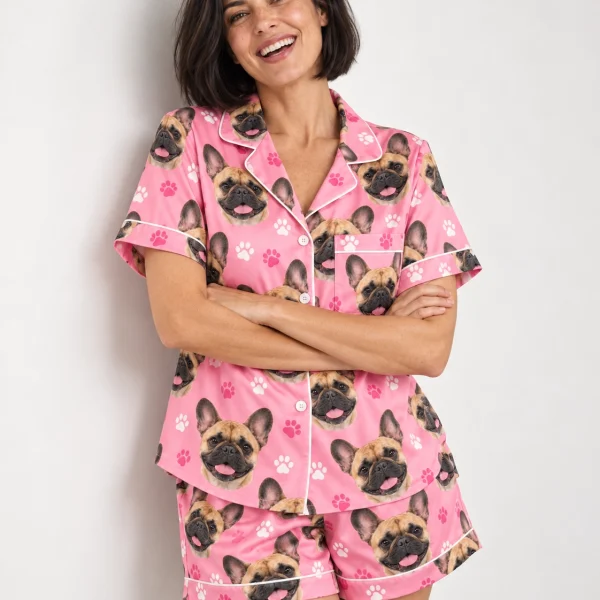 Woman posing in a French bulldog pajama short set, fawn French Bulldog faces on pink paw-print satin — MyDogPics