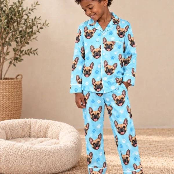 Boy wearing a French bulldog pajamas for kids covered in fawn French Bulldog faces on light blue paw-print satin — MyDogPics