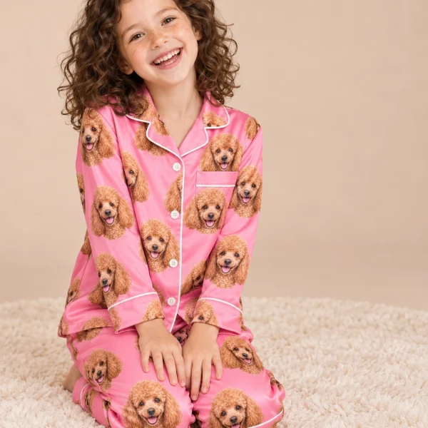 Girl sitting in girls poodle pajamas covered in apricot Poodle faces — MyDogPics