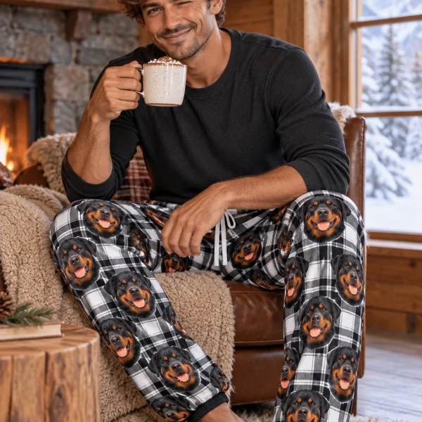 Man sitting in rottweiler pajama pants covered in black-and-mahogany Rottweiler faces — MyDogPics