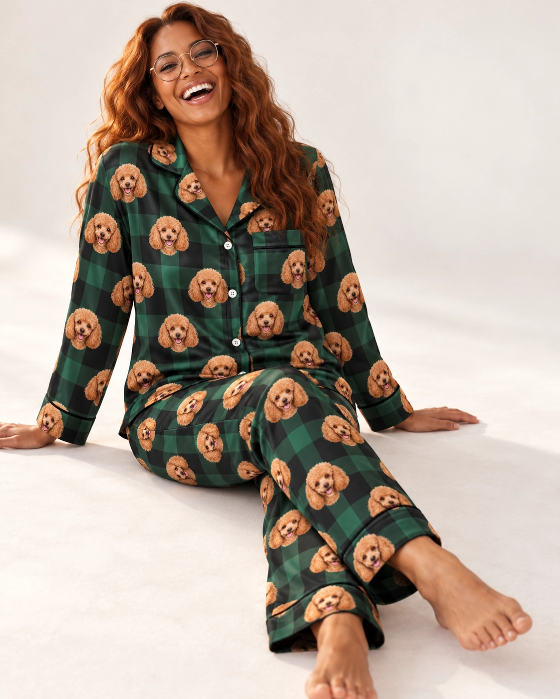 Women’s Poodle Christmas Pajamas – Sitting, Green Plaid | MyDogPics Woman sitting in womens poodle Christmas pajamas covered in apricot Poodle faces — MyDogPics